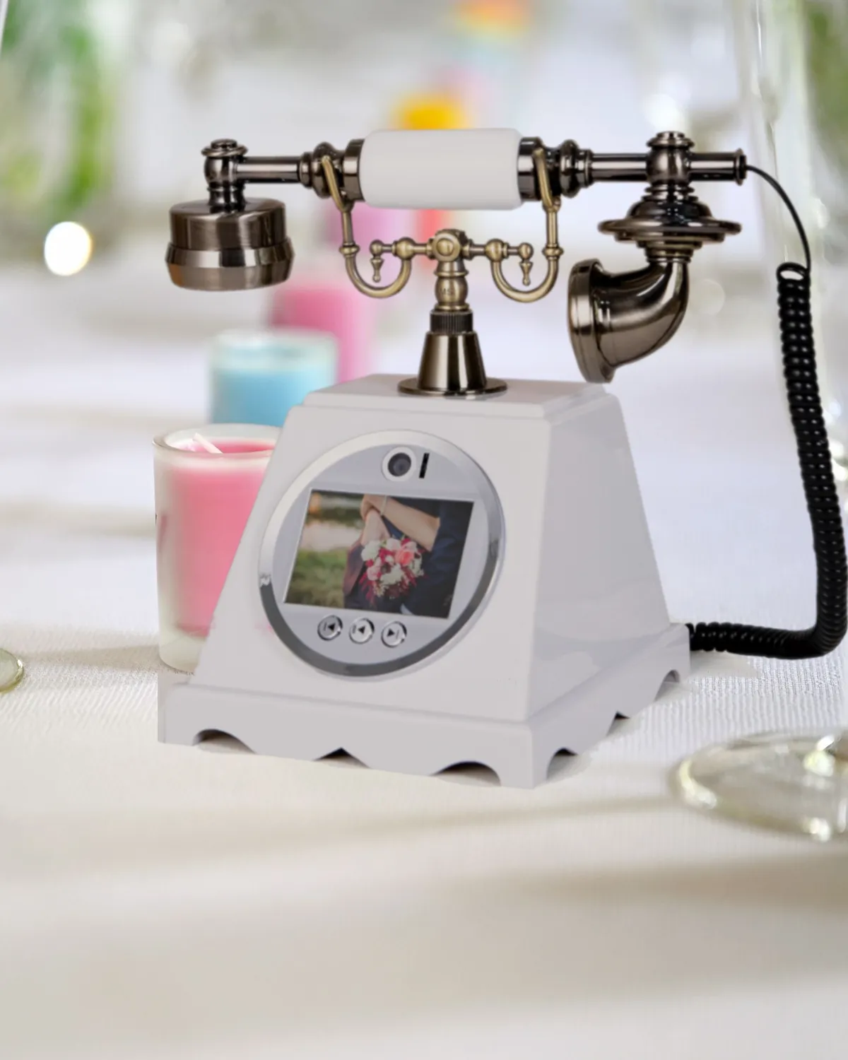 Le combiné à caméra blanc sur une nappe blanche, entre des bougies pastel et des flûtes